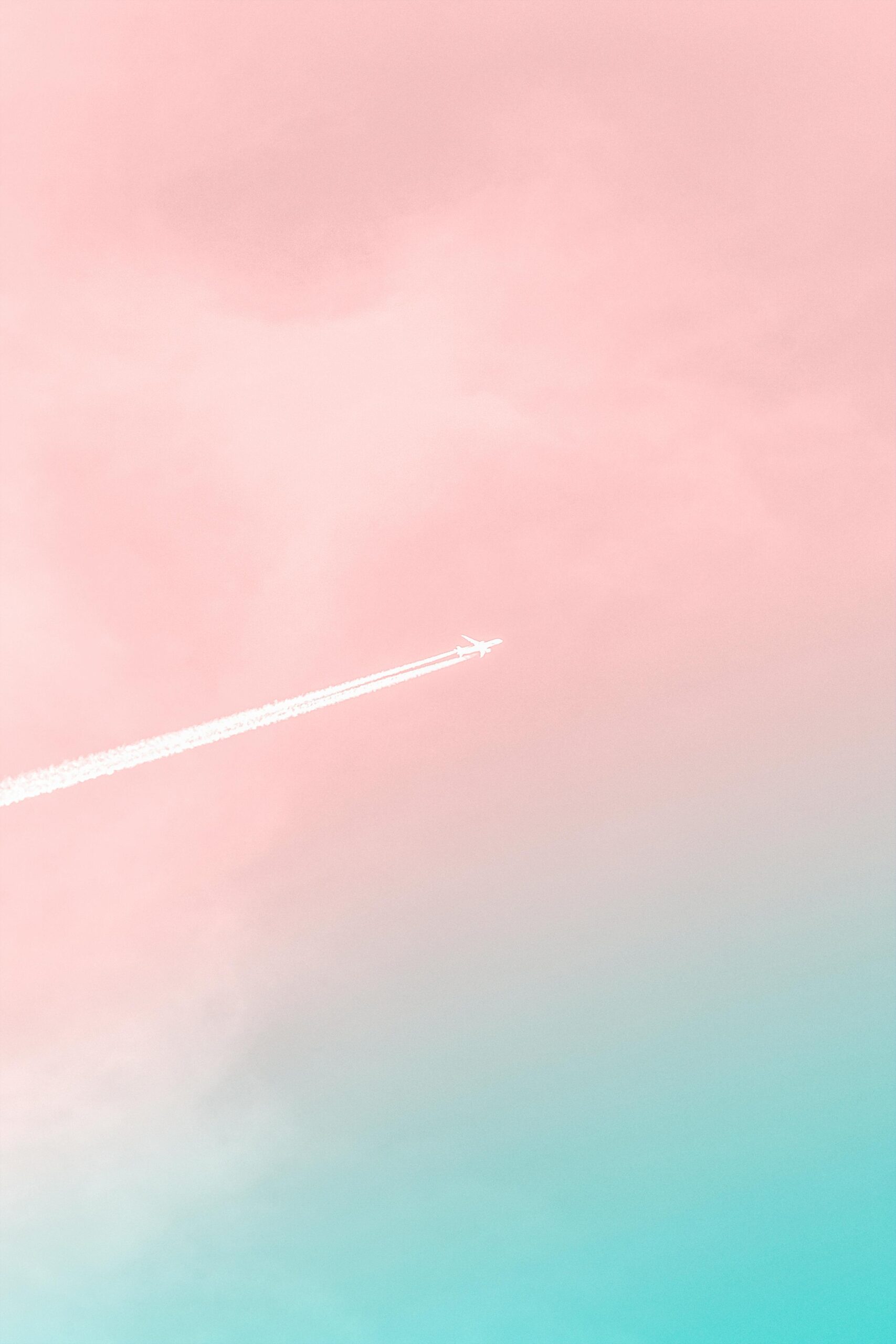 A serene view of an airplane soaring through a pastel pink and blue sky, leaving a contrail.